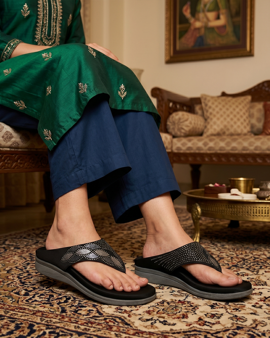 Women's black fabric thong flats with embellished leaf-motif strap, on-foot view