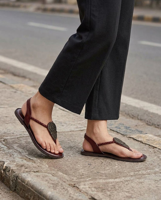 Women's maroon leather thong flat sandals with metal ornament and back strap, on-foot view